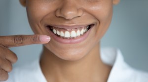 a woman smiles and points at her teeth