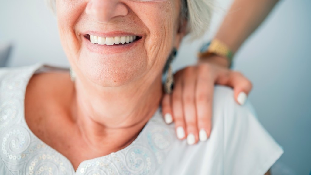 a smiling elderly dental patient with a female hand on her shoulder